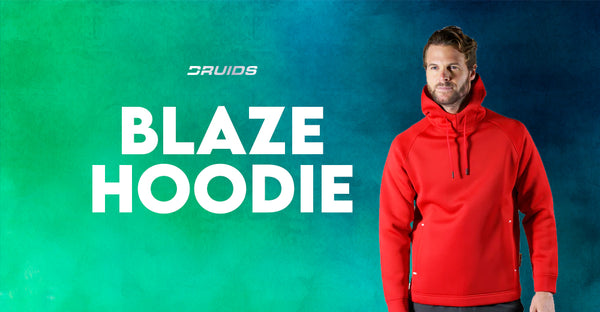 A man modeling the Druids Blaze Hoodie in bright red with a full hood and front pocket, the word 'BLAZE HOODIE' in large white letters to the side, set against a teal textured background.