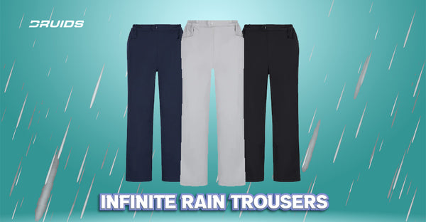 A lineup of three pairs of Druids rain trousers in navy blue, light gray, and black, designed for infinite protection against rain, displayed with the text 'Infinite Rain Trousers' and falling rain graphic in the background.