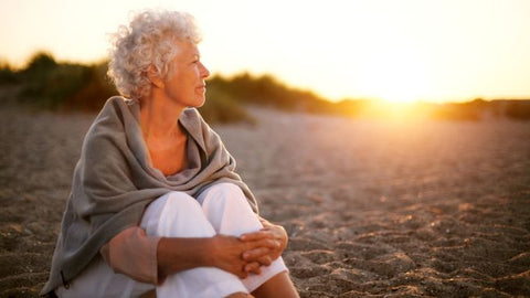 Old woman sitting on the beach looking away 