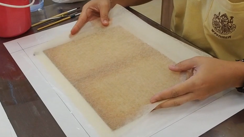 Paper conservation - Placing a thin sheet of kozo paper on top of the original paper
