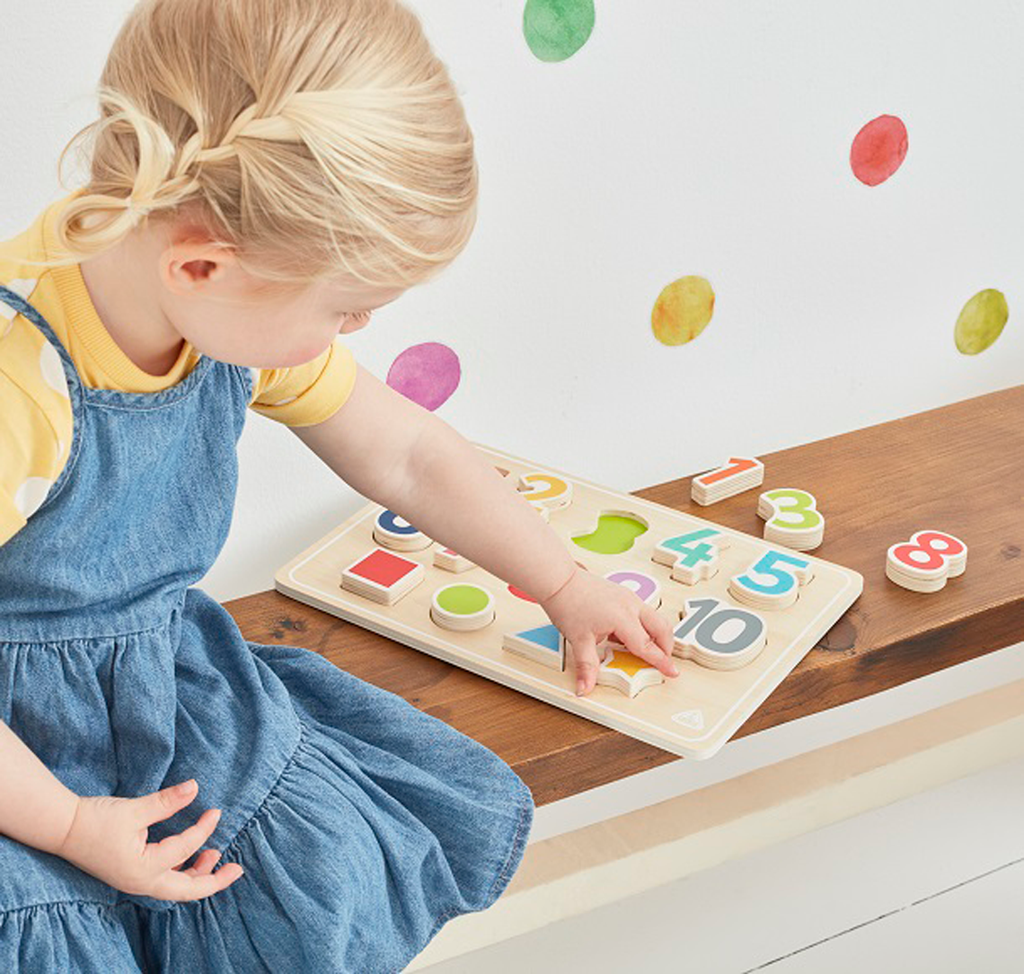 Adorable girl is playing with wooden number puzzles 