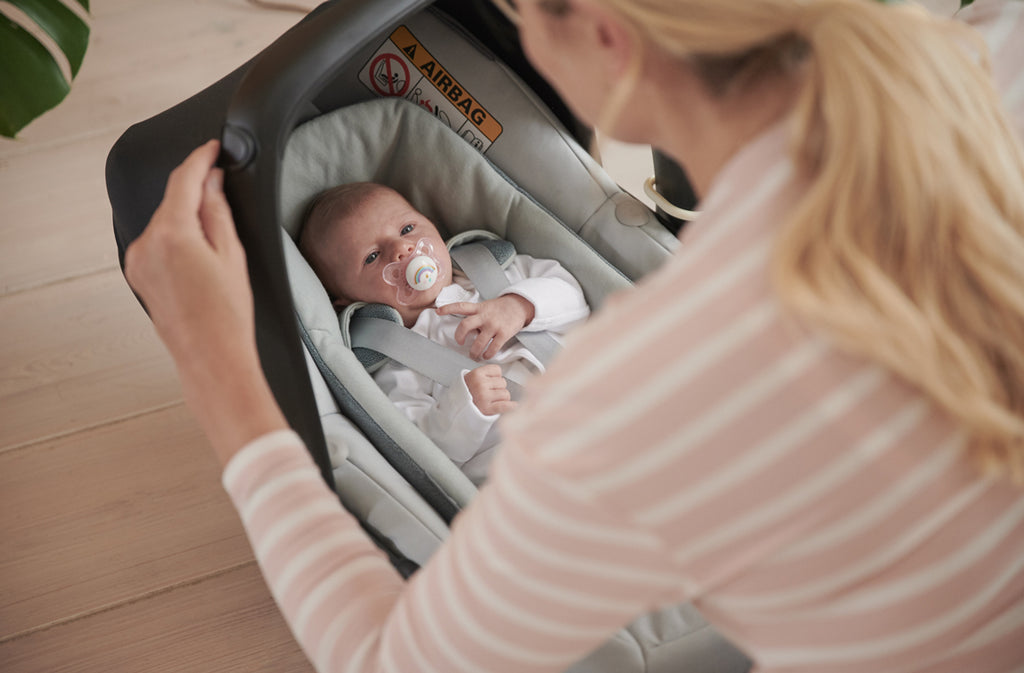 Mother adjusts the baby carrier for her newborn