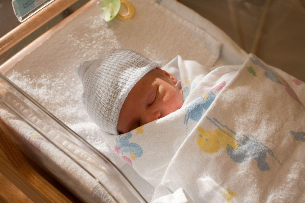 A swaddled newborn baby sleeping in a crib