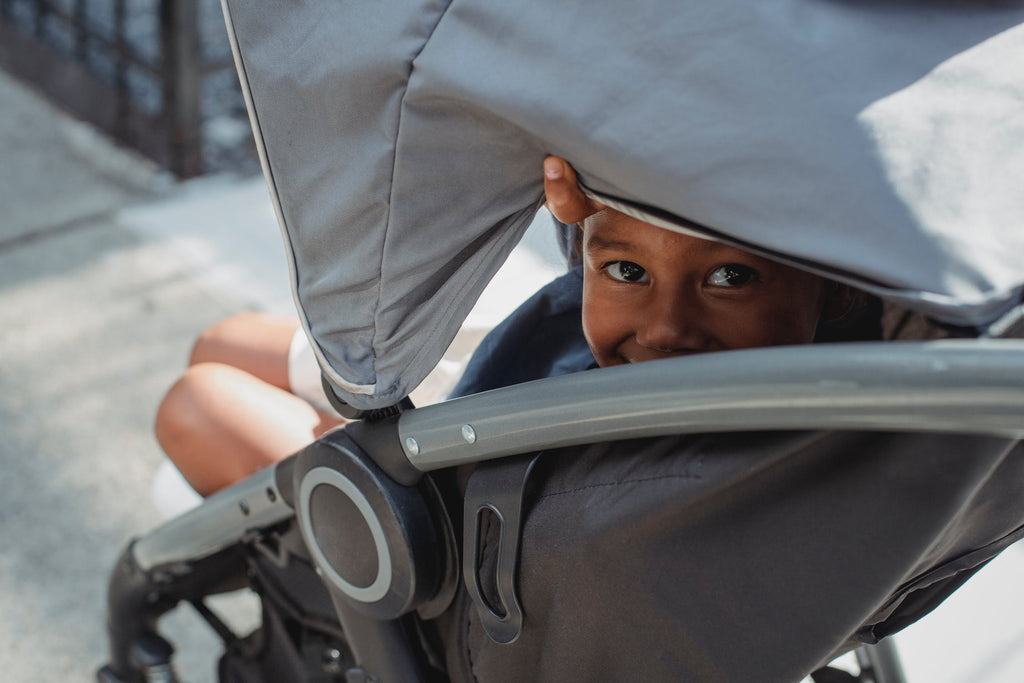 Toddler sitting in a grey stroller 