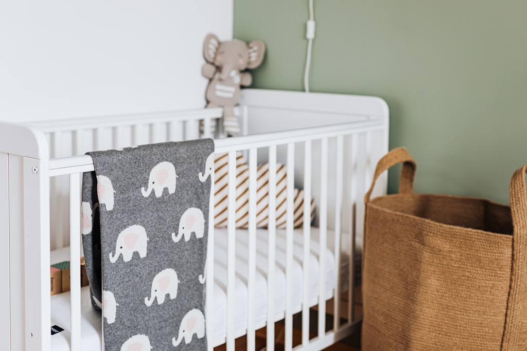 White wooden crib with baby blanket in nursery room 