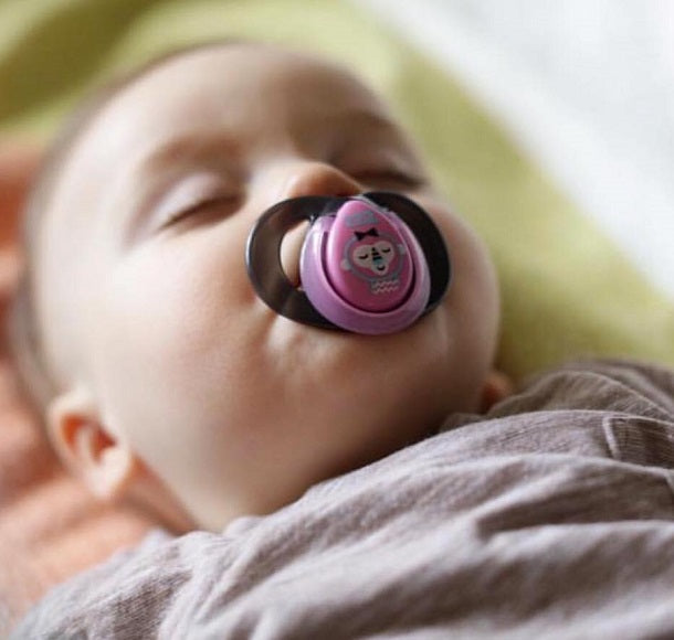 Adorable baby sleeping with a soother