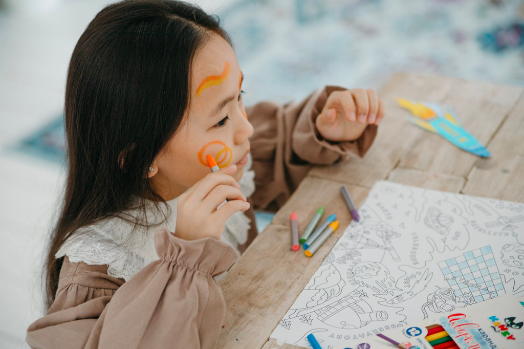 Young girl drawing her face with crayons 