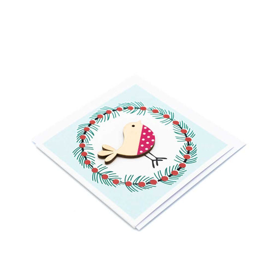 Load image into Gallery viewer, Square card with white envelope tucked inside, white background. Wooden robin decoration at the centre of a Christmas wreath.

