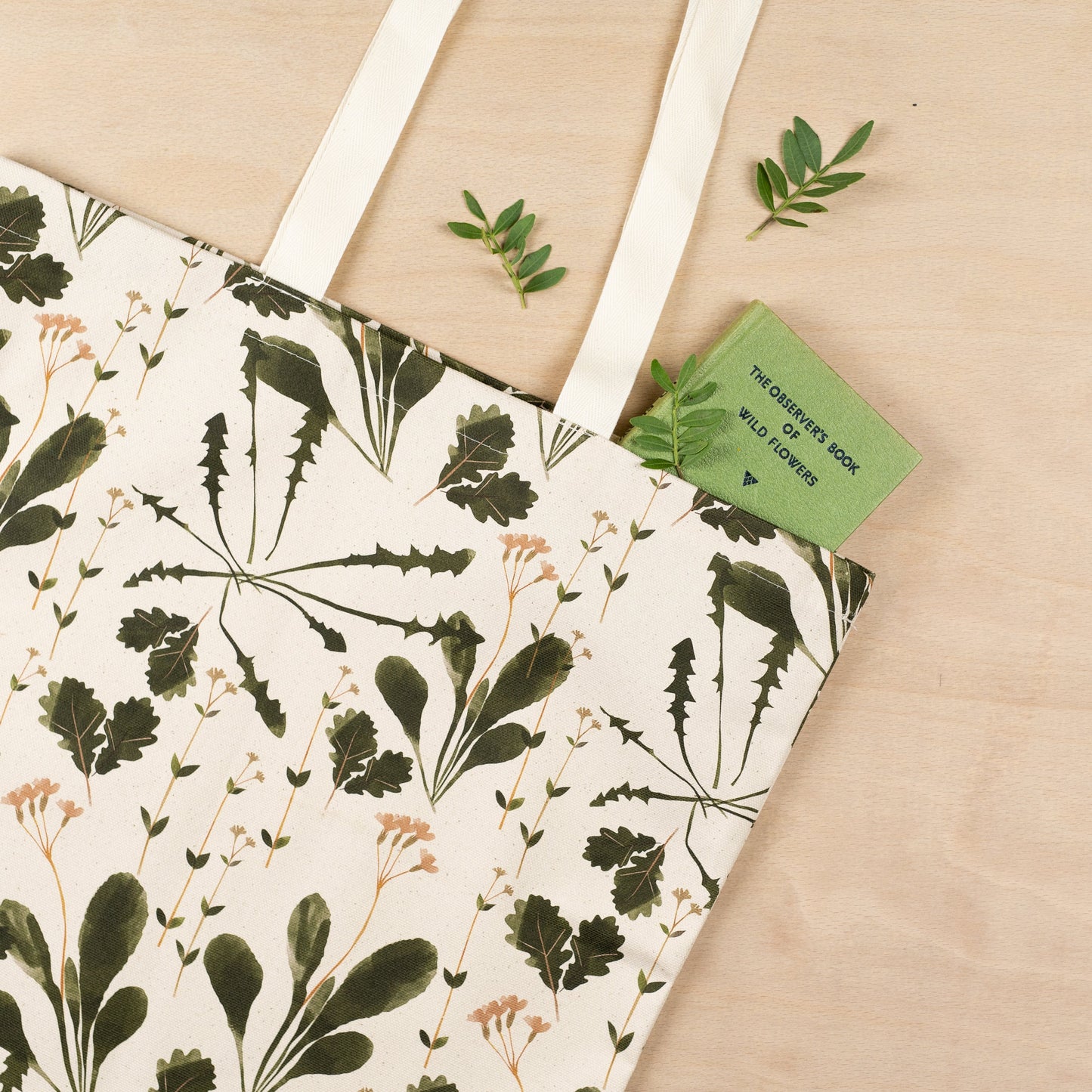 Load image into Gallery viewer, Lifestyle shot up close of tote bag on a wooden surface with a green book partially out of the top.
