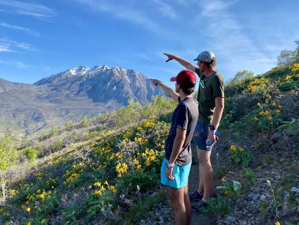 Two hiking and trail running friends pointing toward Mount Timpanogos