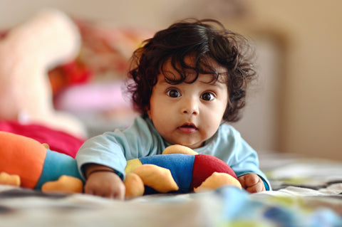 Baby playing with eco-friendly toys and wearing eco-friendly clothes.