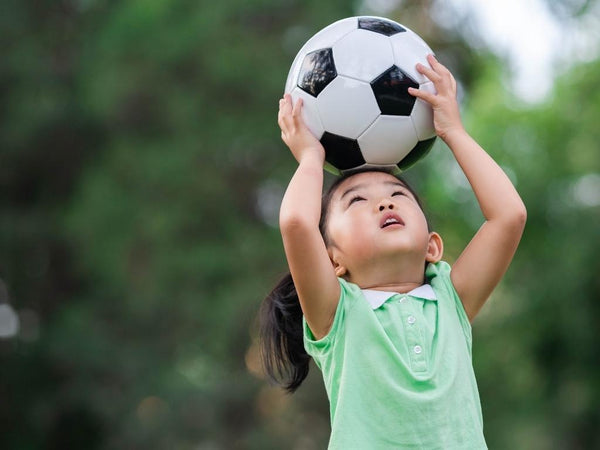 Erziehung ohne Klischees: Mädchen köpfelt mit Fußball