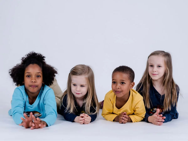 Vier Kinder mit pauakids Kleidung am Boden liegend, Kopf voran