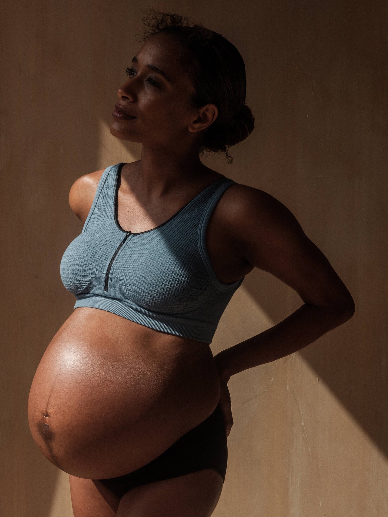 Pregnant woman in sports bra using smart phone in doorway - Stock