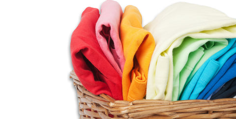 A wicker basket filled with brightly colored t-shirts, each folded neatly and arranged in an orderly fashion, displaying a spectrum of vibrant hues and patterns.