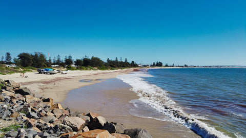 Experience outdoor activities on a rocky, white sand under a blue sky in the coastline of Stockton beach,, NSW.