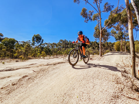 Wearing a blue helmet, backpack, a biker is exploring the You Yangs mountain bike park and Kurrajong area on a hot day in Little River Victoria Australia