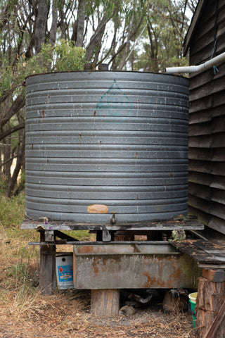 Metal Water Storage Tank Outside Next To A Cabin