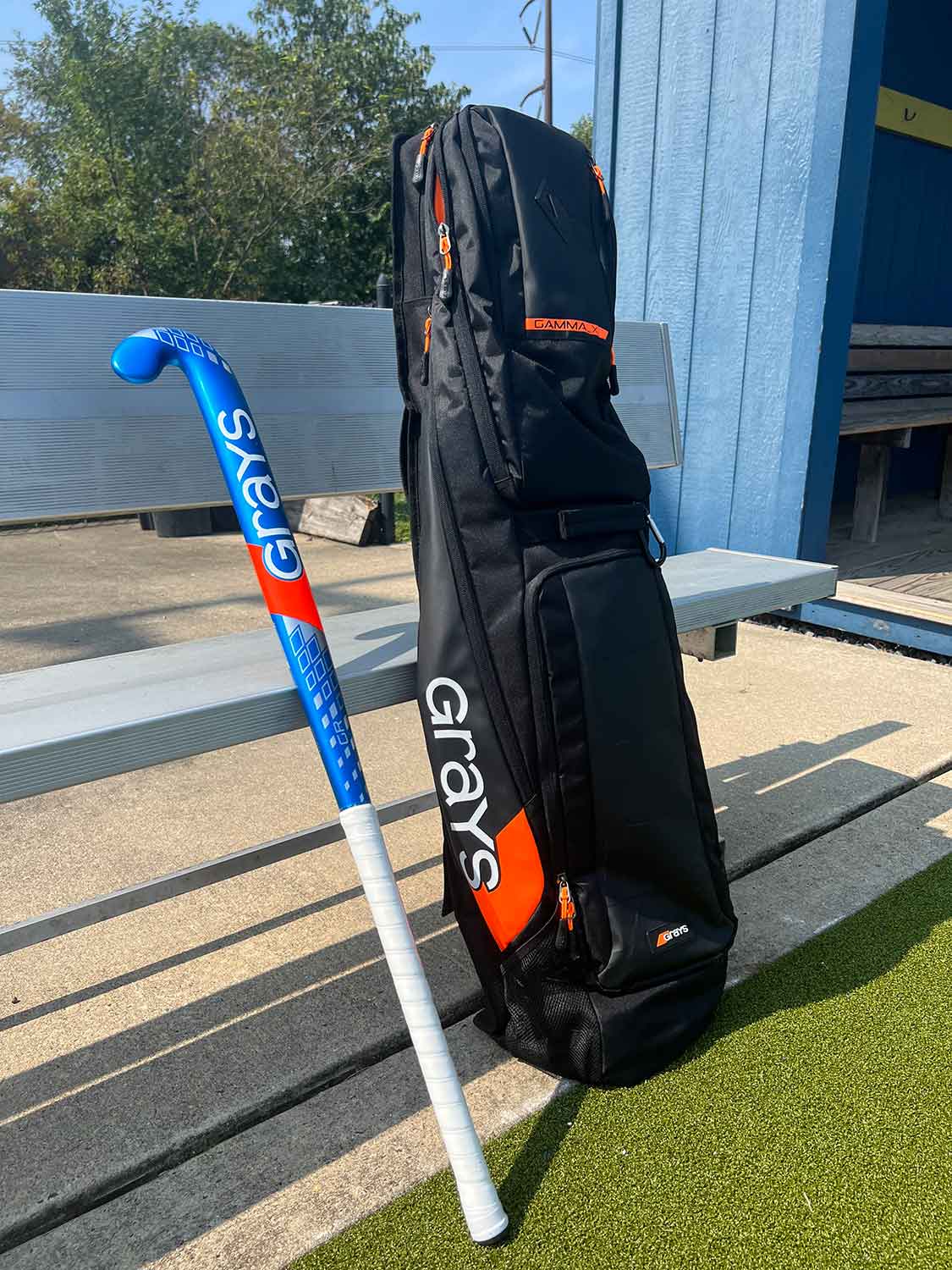 Field hockey stick and bag leaning on a bench.