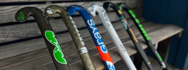 Five field hockey sticks leaning against a bench.