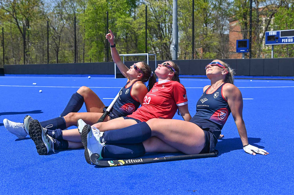 three field hockey players looking up at the eclipse