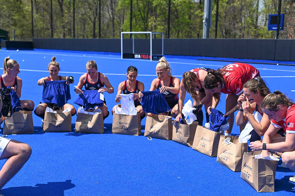 USA field hockey team sitting in a circle opening bags of apparel.