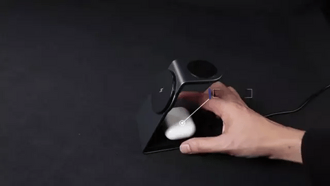 chargeur magsafe Apple sur bureau noir avec une main qui met en charge par induction à la suite une paire d'airpods une apple watch et un iphone