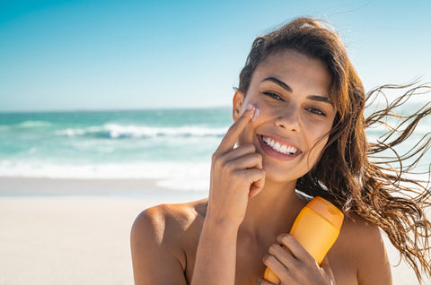Woman at the beach holding sunscreen