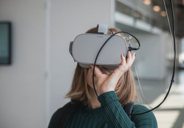 Woman in sweater holding VR goggles