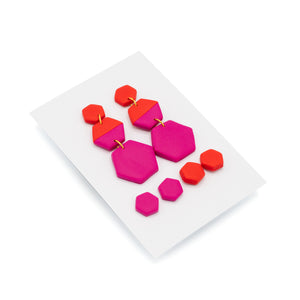Pink and Red earrings set in hexagon shapes photographed against a white background