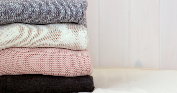 Stack of knitted jumpers in black, pink and grey