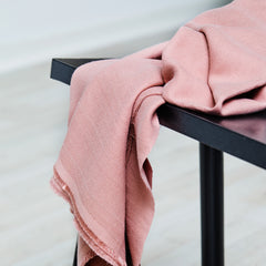 Pink woven sewing fabric draped over black bench