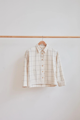 White grid over shirt hanging on a wooden rail