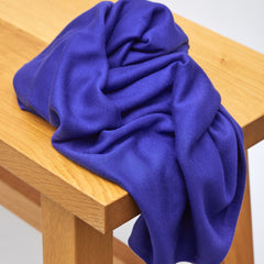 Bright blue jersey knit sewing fabric piled on top of table
