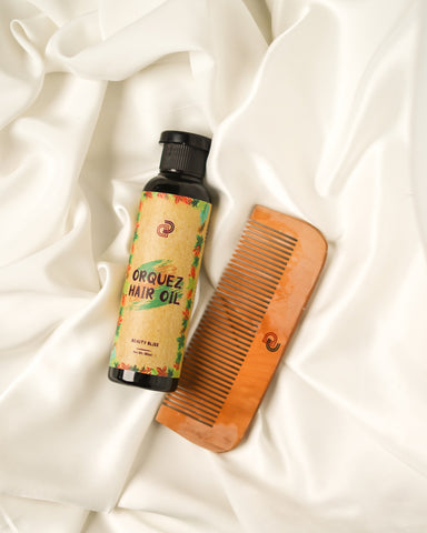 An image of Orquez Hair Oil bottle alongside a wooden comb, laid on a luxurious silk background, evoking elegance and the nurturing care provided by the hair oil.