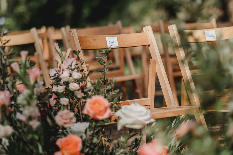 Photograph of wedding decoration, wooden chairs and flowers are visible