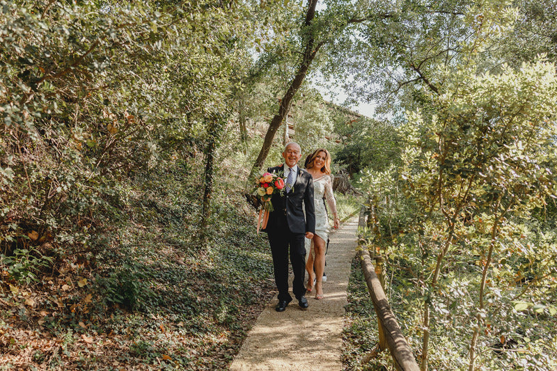 Photograph of Mireia walking with a man, she wears her wedding dress and the man wears a formal suit