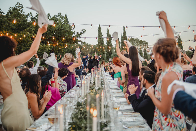 Photograph from one end of the wedding guest table, where the bride and groom are seen celebrating