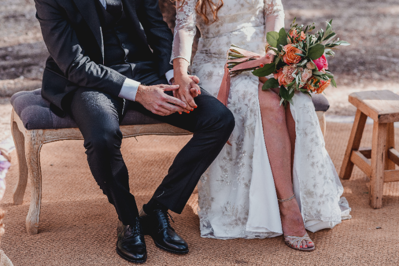 Photograph of Pedro and Mireia at their wedding, sitting holding hands