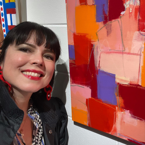artist standing in front of her painting with red, purple and pink paints