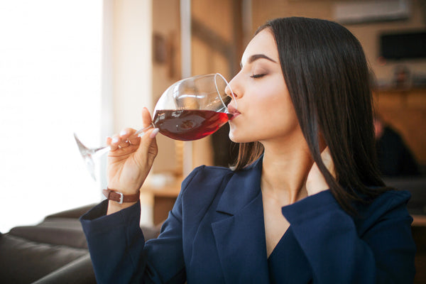 Jeune femme buvant du vin rouge