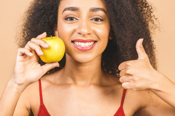 Jeune femme souriante tenant une pomme 
