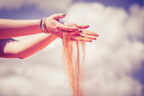 sand falling through a woman's hands