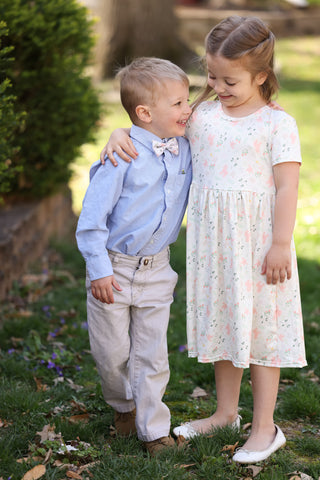 two children standing outside in Easter clothes laughing.