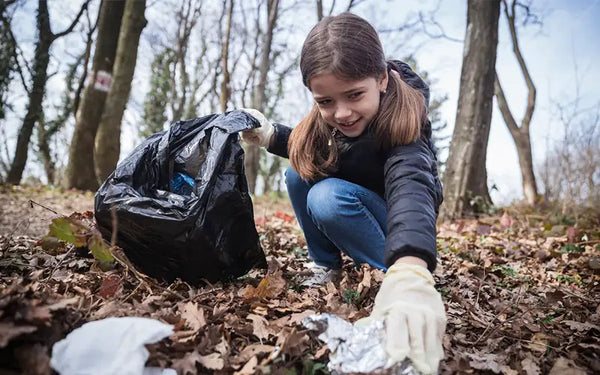 flicka plockar skräp i en skog på grund av klimatboven som är överkonsumtion av livsmedel med snabba kolhydrater