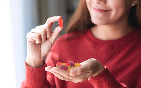 Sötsugen kvinna med lågt blodsocker håller upp en gummibjörn