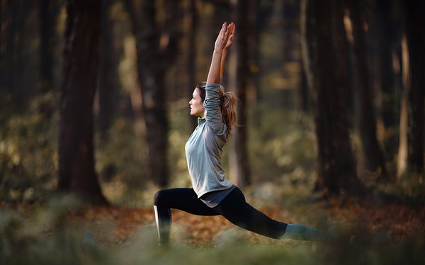 kvinna med balanserat blodsocker på yogaretreat, gör yoga i skogen