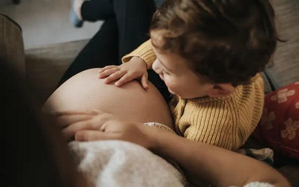 mamma med graviddiabetes visar sin mage för ett barn som klappar den