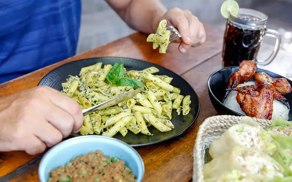 Man äter kolhydrater i form av pasta och får en kraftig blodsockerhöjning på grund av läsken som han dricker till