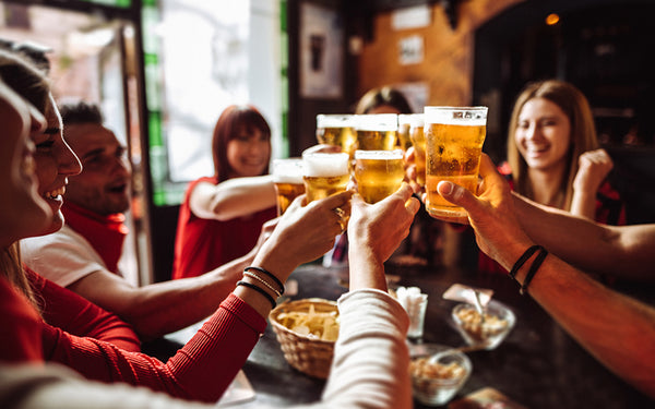 Stort sällskap ökar sitt energiintag med alkohol i form av öl, skålar med ölglas på en pub